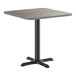 A square standard height table with a reversible gray and white laminated top and a black cast iron base.
