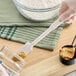 A gloved hand uses a white OXO Good Grips jar spatula to spread peanut butter on a jar.