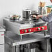 A woman cooking food on an Avantco countertop electric range.