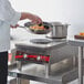 A chef cooking food on an Avantco solid French-style countertop electric range.