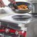 A person cooking vegetables in a pan on an Avantco countertop electric range.