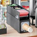 A black KleanTake coffee supply organizer on a counter with containers of condiments.