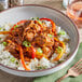 A bowl of Jackfruit with rice and peppers with a fork and a glass of wine.