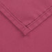 A close up of a mauve rectangular cloth table cover with a hemmed edge.