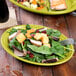 A Fiesta Lemongrass oval china platter with a salad on it, with a fork and a glass of soda.