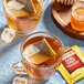 A glass mug of Twinings Earl Grey tea with a tea bag in it next to a jar of honey.