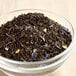 A bowl of black tea with brown leaves and blue and white flowers.