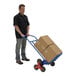 A man using the blue Vestil steel stair hand truck to move boxes.