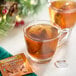 A mug of Twinings Gingerbread Joy Tea next to a packet of tea bags.