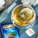 A glass cup of Twinings Nightly Calm herbal tea with a tea bag in it.