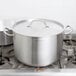 A large silver Vollrath sauce pot with a lid on a stove.