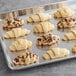 A tray of Schulstad ready to bake assorted filled croissants on a gray surface.