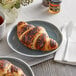 A plate with a chocolate hazelnut filled croissant on a table with a cup of tea.