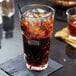 A glass of brown liquid with ice in an Anchor Hocking New Orleans cooler glass.