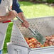 A man using a stainless steel paddle to cook food on a grill.