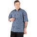 A man wearing an Uncommon Chef Havana short sleeve chef coat with mesh back.