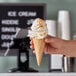 A hand holding a JOY waffle cone with ice cream.