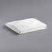 A stack of folded white Oxford Super Blend Queen Size bed toppers on a gray surface.