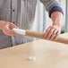 A person holding a long brown Kraft paper mailing tube.