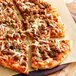 A pizza with plant-based Italian sausage and cheese on a wooden board.