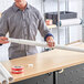 A man holding a Lavex white mailing tube next to a roll of paper.