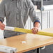 A man holding a rolled up gold paper mailing tube.