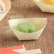 A small green flower shaped food in a wooden bowl.