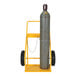 A yellow Vestil steel cylinder cart holding a large gas cylinder.