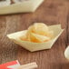 An EcoChoice wooden paper boat filled with food.