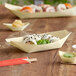 A wooden food boat filled with sushi on a table in a sushi bar.