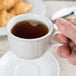 A person holding a white Tuxton Chicago china cup filled with coffee.