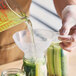 A person using a Choice white plastic canning funnel to pour liquid into a jar.