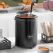 A woman using a ladle to pour soup into an Avantco black soup warmer.