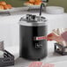 A hand holding a card in a black soup warmer.