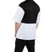 A man wearing a white Uncommon Chef Rogue Pro Vent chef coat with a black and white shirt underneath.
