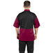 A man wearing a maroon and black Uncommon Chef Rogue Pro Vent chef coat with mesh back.