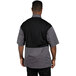 A man wearing a Uncommon Chef Rogue Pro Vent chef coat with a black and grey shirt.