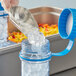 A person using a Vigor Polar cooling paddle to put ice in a clear plastic container on a kitchen counter.