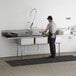 A man washing a Regency stainless steel 3 compartment sink.