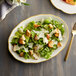 A CAC ivory china platter with a salad topped with croutons and parmesan cheese.