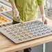 A person pouring a mixture into a Baker's Mark mini muffin pan.