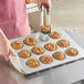 A woman holding a Baker's Mark jumbo muffin pan with muffins in it.
