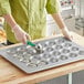 A woman using a Baker's Mark jumbo muffin pan with green handles to bake cupcakes.