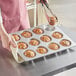 A person holding a muffin in a Baker's Mark jumbo muffin pan.