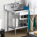 A man standing in a kitchen with a Regency stainless steel dish table undershelf on a counter near a sink.