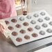 A woman holding a Baker's Mark muffin pan with cupcakes.