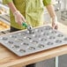 A person using a Baker's Mark muffin pan to put batter into a muffin tin.