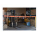 A forklift behind a Banner Stakes wall mount barrier with orange and black belts.