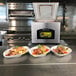 A ARY VacMaster VP321 Chamber Vacuum Packaging Machine with a lid open on a counter with plates of food.