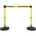 A pair of yellow and black Banner Stakes retractable barriers.